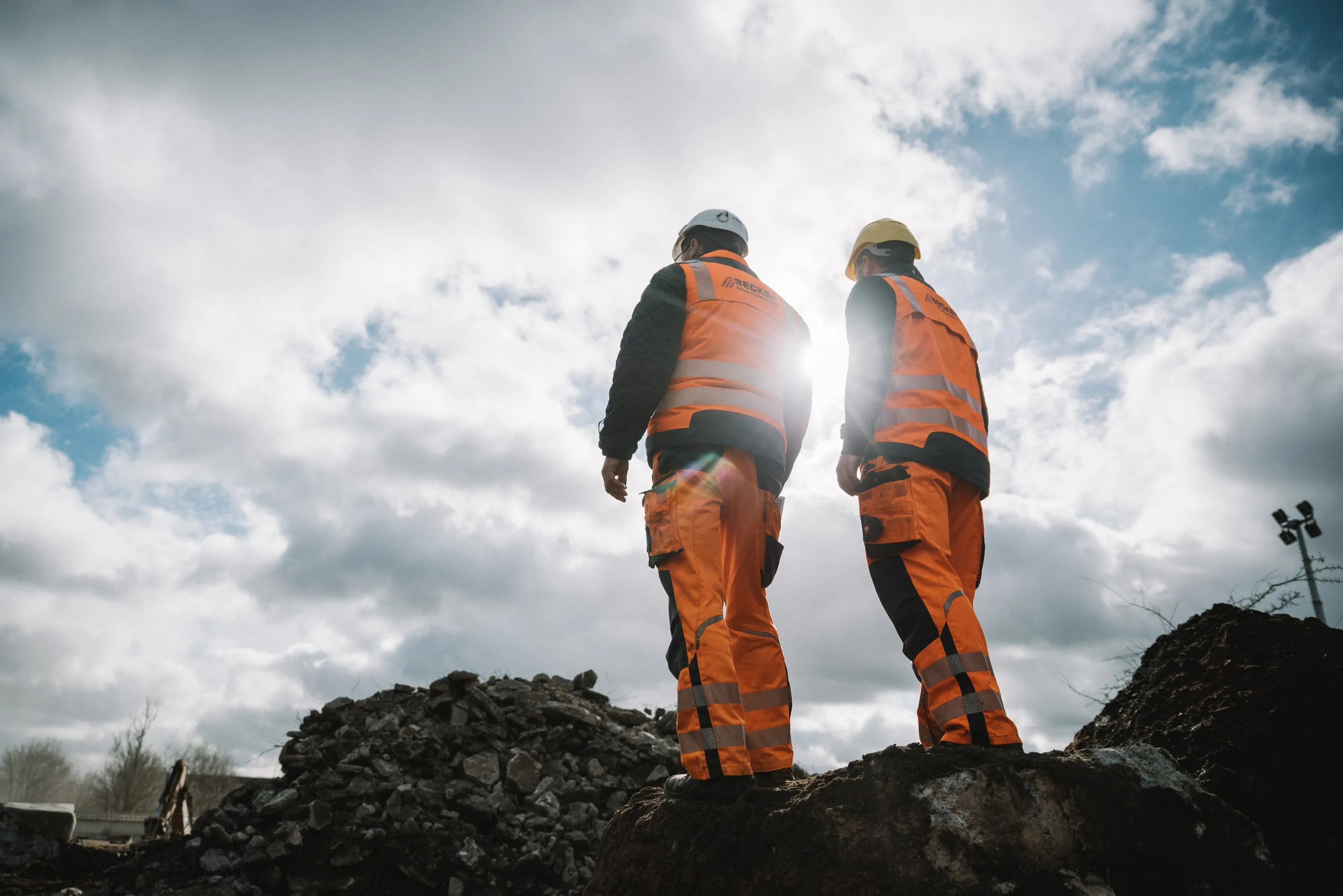 Zwei Bauarbeiter des BECKER Bauunternehmens aus Meppen auf einer Baustelle im Gegenlicht